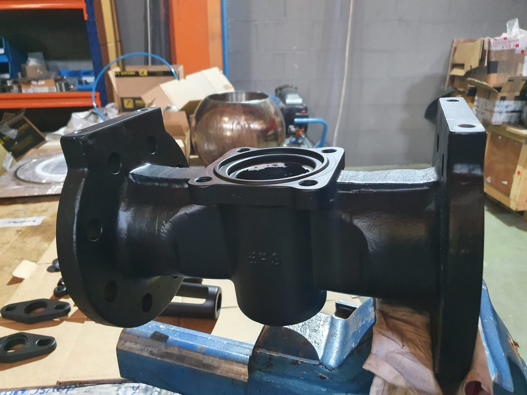 Black plug valve body with flanged ends and upper mounting interface during assembly
